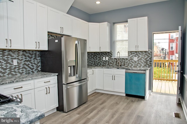 kitchen with light stone counters, appliances with stainless steel finishes, and white cabinets