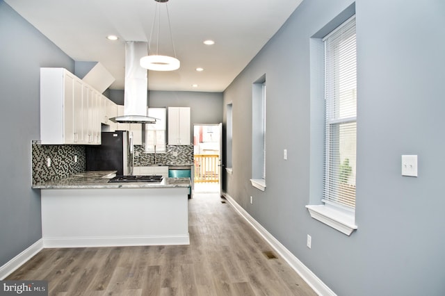 kitchen featuring pendant lighting, white cabinetry, backsplash, stainless steel appliances, and kitchen peninsula