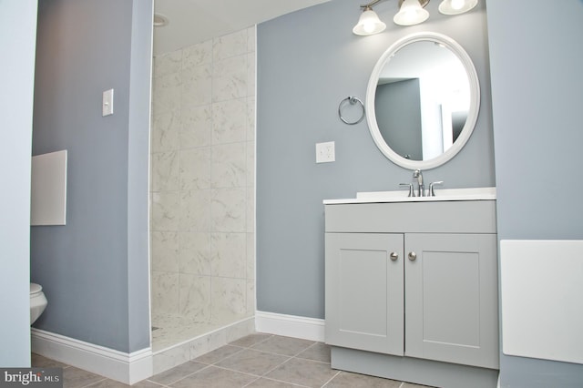 bathroom featuring tile patterned flooring, vanity, toilet, and tiled shower