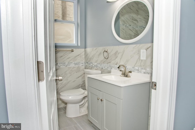 bathroom with vanity, tile walls, and toilet