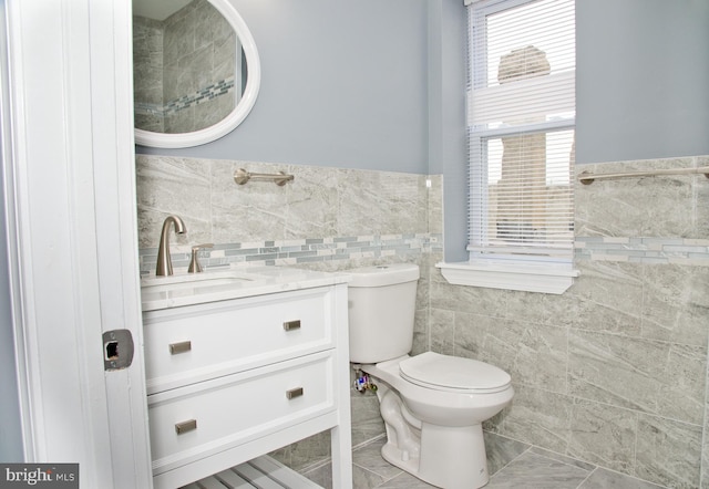 bathroom featuring vanity, tile walls, and toilet