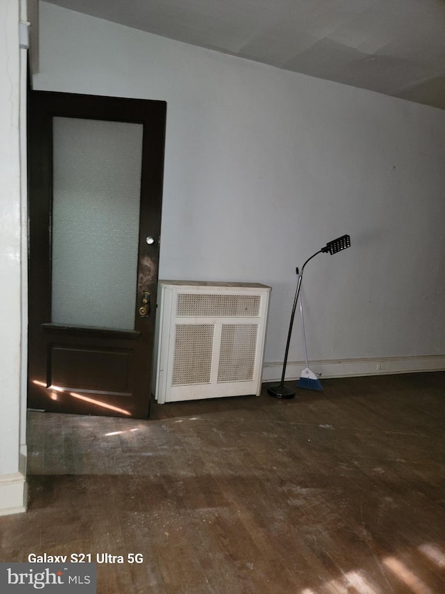 unfurnished room with dark hardwood / wood-style flooring and radiator heating unit