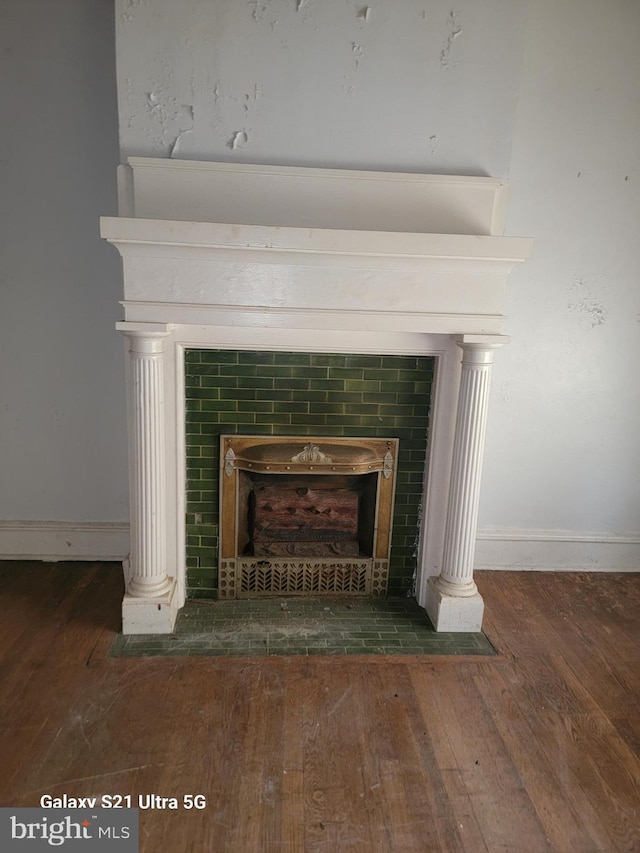 room details with a tiled fireplace and hardwood / wood-style flooring