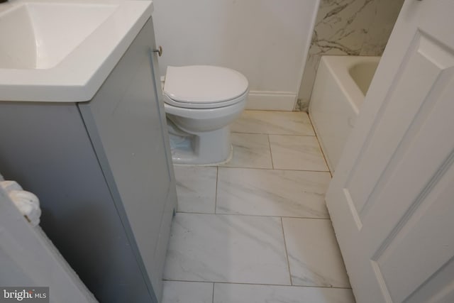 bathroom with vanity, a bathing tub, and toilet