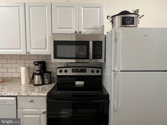 kitchen featuring white cabinetry, white appliances, light stone countertops, and decorative backsplash