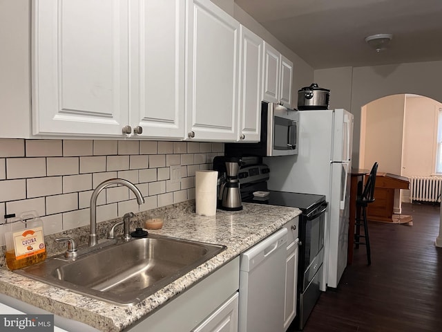 kitchen featuring appliances with stainless steel finishes, radiator heating unit, white cabinetry, sink, and decorative backsplash