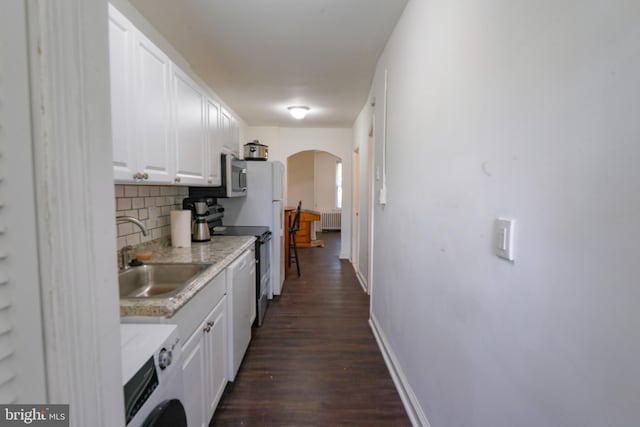 kitchen featuring sink, radiator, white cabinetry, backsplash, and washer / dryer