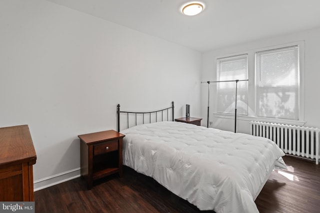 bedroom with radiator heating unit and dark hardwood / wood-style flooring