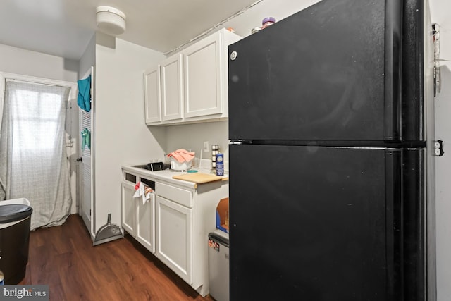 kitchen with black refrigerator, white cabinetry, and dark hardwood / wood-style floors