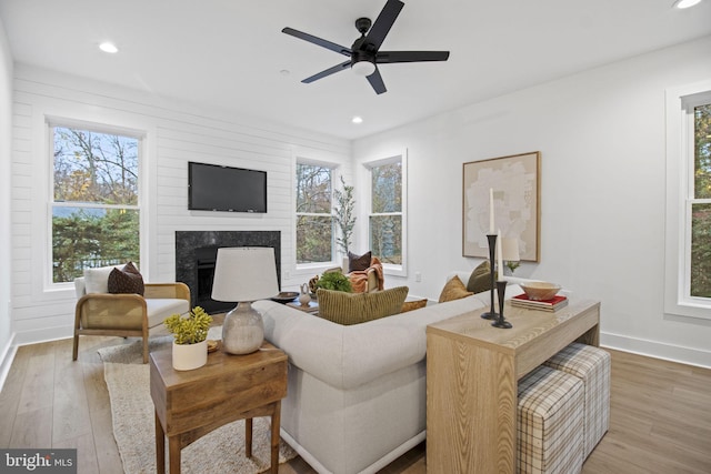 living area featuring ceiling fan, recessed lighting, wood finished floors, a high end fireplace, and baseboards