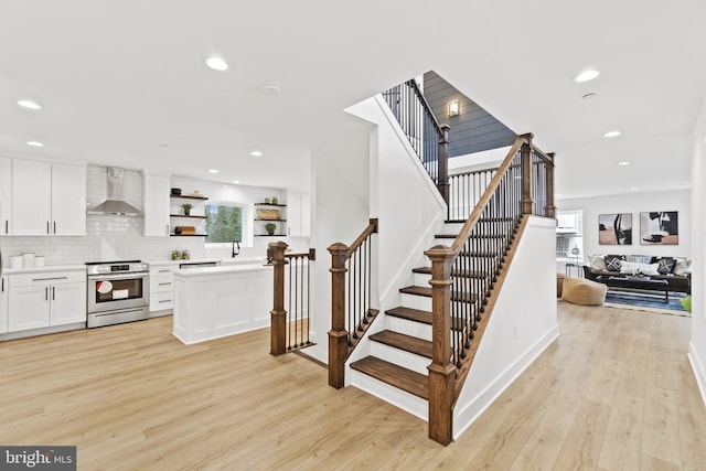 stairway with plenty of natural light, wood finished floors, and recessed lighting