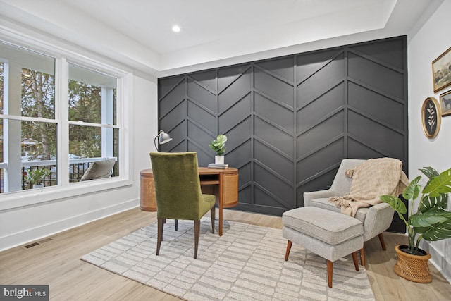 office featuring light wood-style flooring, visible vents, and a decorative wall