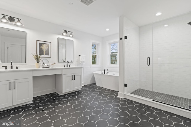 full bath featuring a freestanding bath, a stall shower, a sink, and visible vents