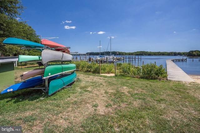 exterior space featuring a dock, a water view, and a lawn