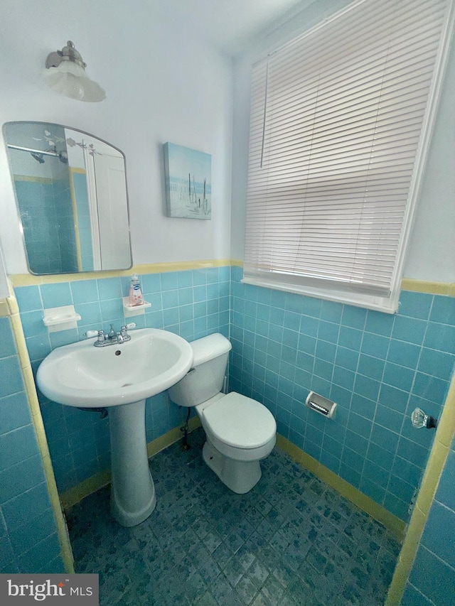 bathroom with toilet and tile walls