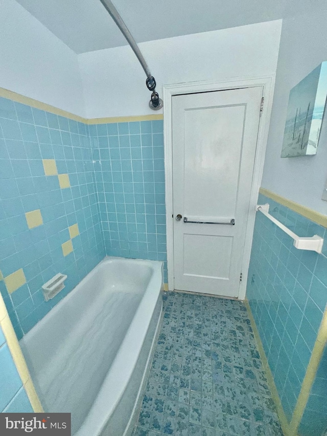 bathroom featuring bathing tub / shower combination and tile walls