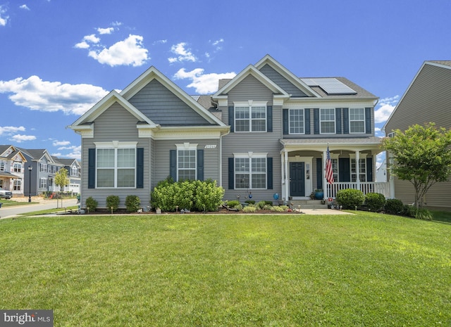 view of front of house with covered porch, solar panels, and a front yard