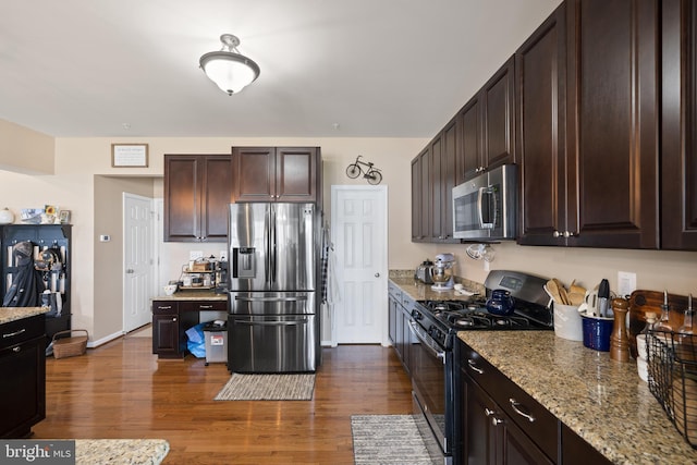 kitchen with appliances with stainless steel finishes, dark wood-type flooring, dark brown cabinetry, and light stone counters