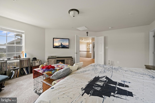 bedroom featuring a warm lit fireplace, light carpet, and visible vents