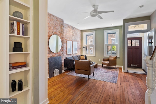 living area with hardwood / wood-style flooring, baseboards, built in features, and ceiling fan