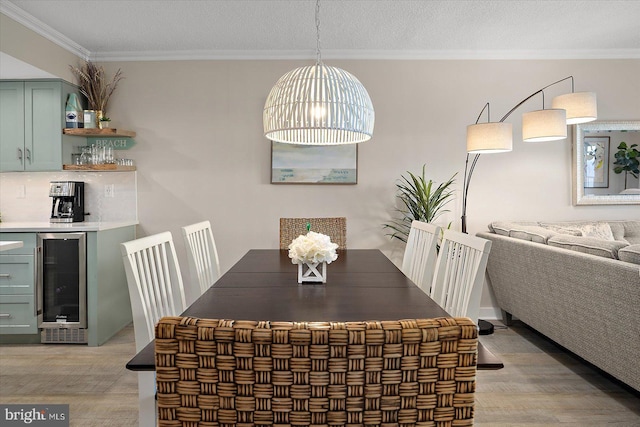 dining space featuring crown molding, wine cooler, and light hardwood / wood-style floors