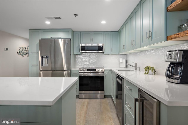 kitchen featuring stainless steel appliances, beverage cooler, light stone countertops, and light hardwood / wood-style flooring