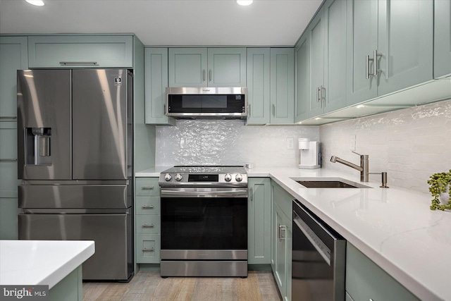 kitchen featuring sink, backsplash, stainless steel appliances, light stone counters, and light wood-type flooring