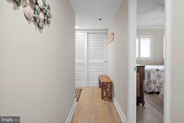 corridor with ornamental molding and light wood-type flooring