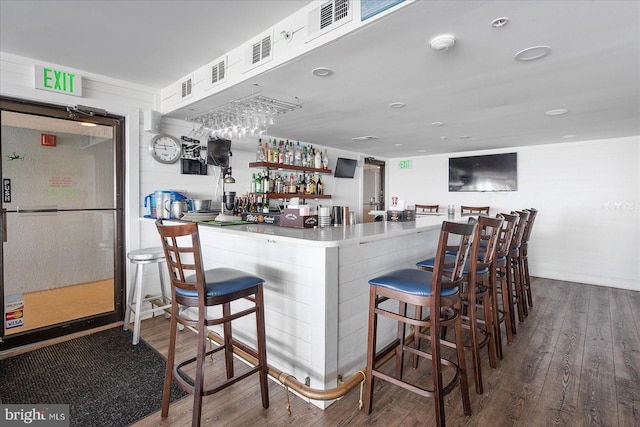 bar featuring wood-type flooring, fridge, and white cabinets