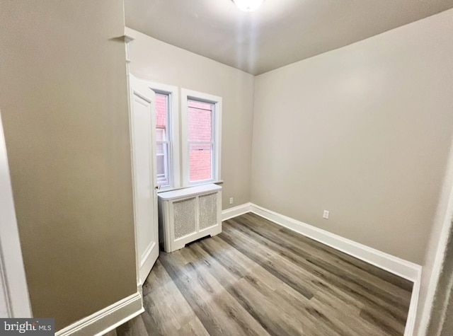 empty room featuring wood-type flooring and radiator