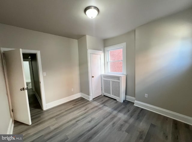 unfurnished bedroom featuring dark wood-type flooring and radiator