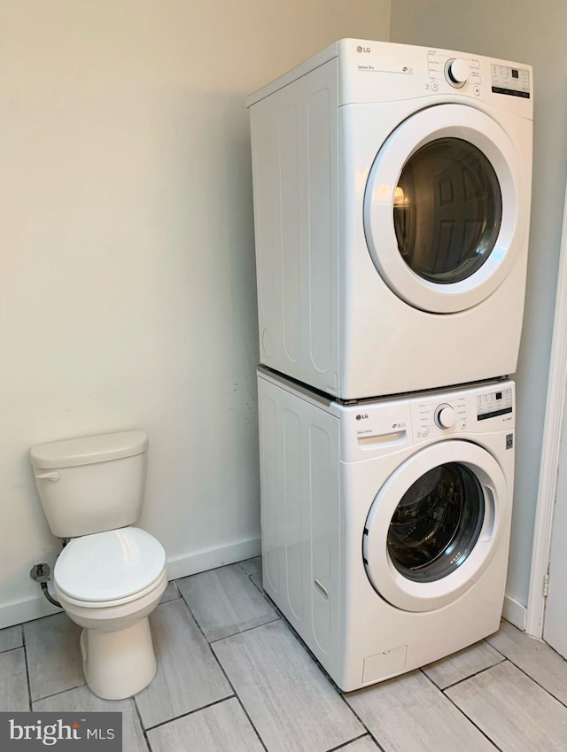 clothes washing area featuring stacked washing maching and dryer