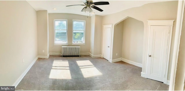 interior space with ceiling fan, radiator, and light carpet