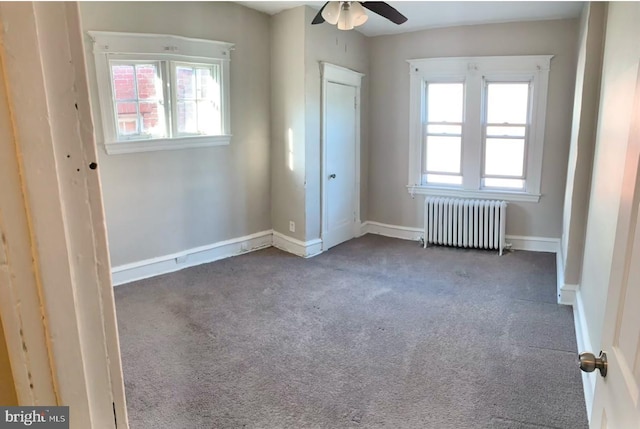 unfurnished room featuring radiator, ceiling fan, a healthy amount of sunlight, and carpet