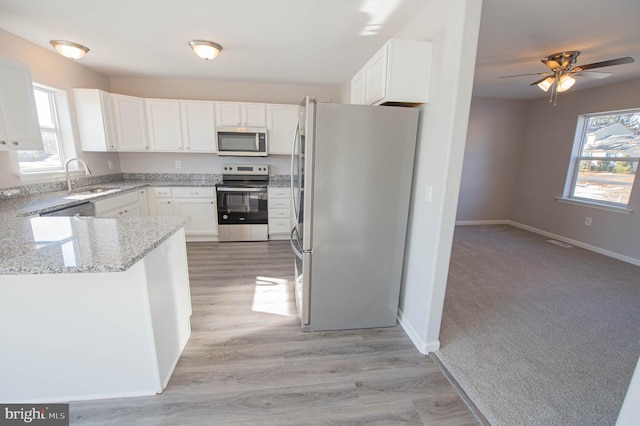 kitchen with a healthy amount of sunlight, appliances with stainless steel finishes, sink, and white cabinets