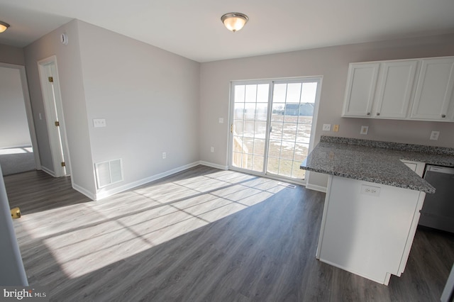 kitchen with white cabinetry, hardwood / wood-style floors, stainless steel dishwasher, and dark stone countertops