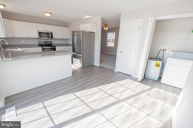 kitchen with washer / dryer, sink, light stone counters, stainless steel appliances, and white cabinets