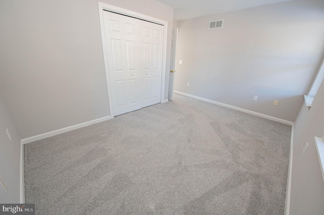 unfurnished bedroom with light colored carpet and a closet