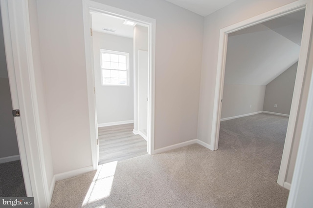 hallway with light colored carpet and vaulted ceiling