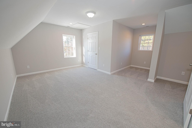 additional living space featuring vaulted ceiling and light carpet