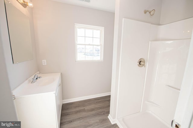 bathroom with walk in shower, vanity, and hardwood / wood-style floors