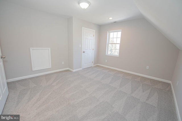 bonus room with lofted ceiling and light colored carpet