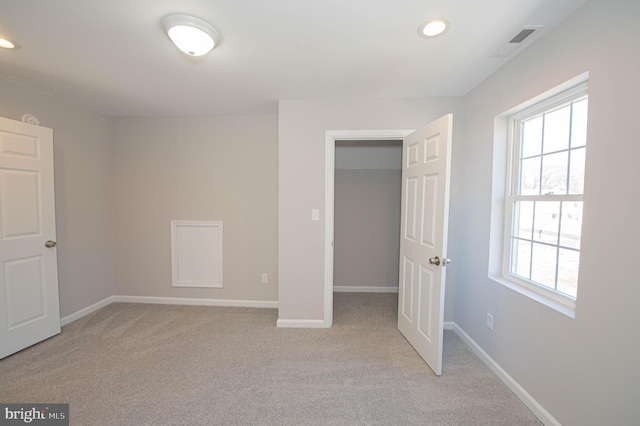 unfurnished bedroom featuring a walk in closet, light colored carpet, and a closet