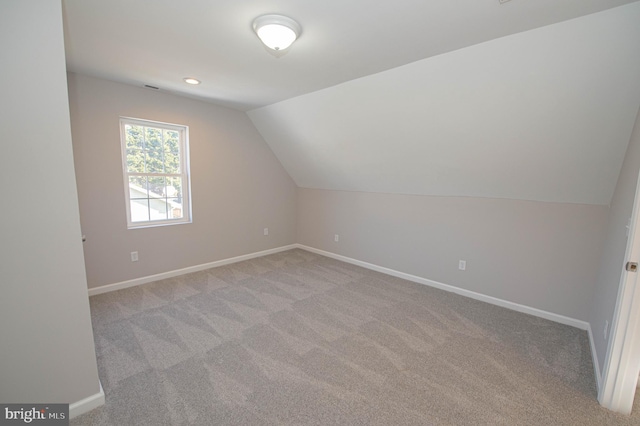 additional living space with vaulted ceiling and light carpet