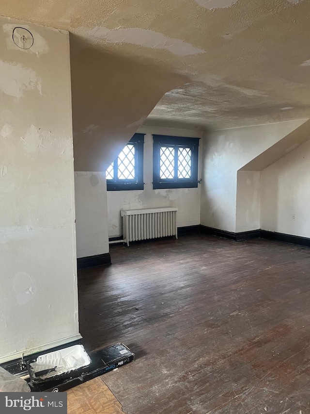 bonus room with radiator heating unit, dark hardwood / wood-style flooring, and a textured ceiling