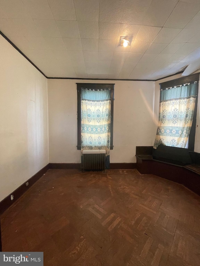 empty room featuring dark parquet flooring and radiator