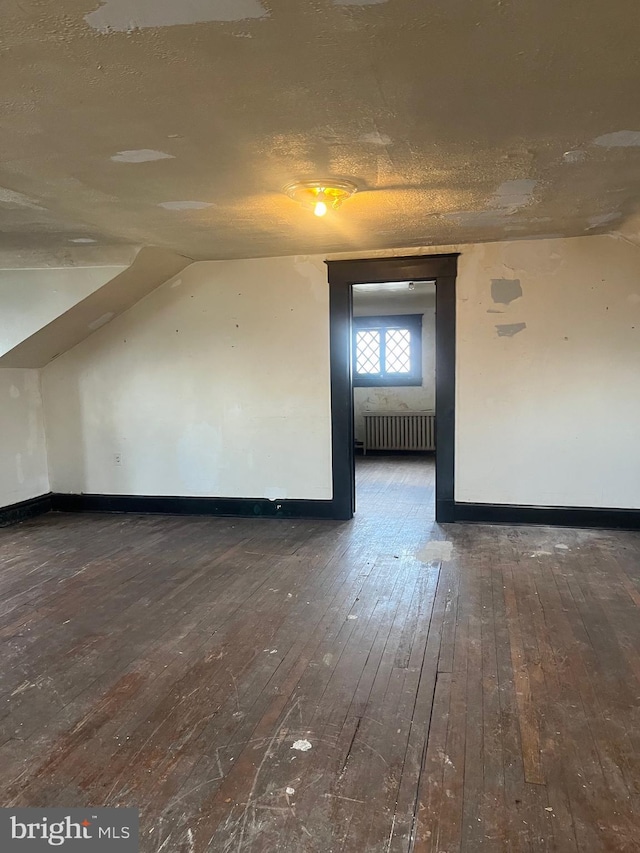 bonus room with lofted ceiling, dark hardwood / wood-style floors, radiator, and a textured ceiling