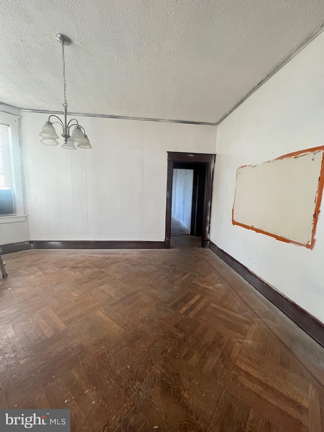 unfurnished room with a notable chandelier, dark parquet floors, and a textured ceiling