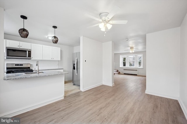 kitchen with sink, white cabinets, hanging light fixtures, stainless steel appliances, and light stone countertops