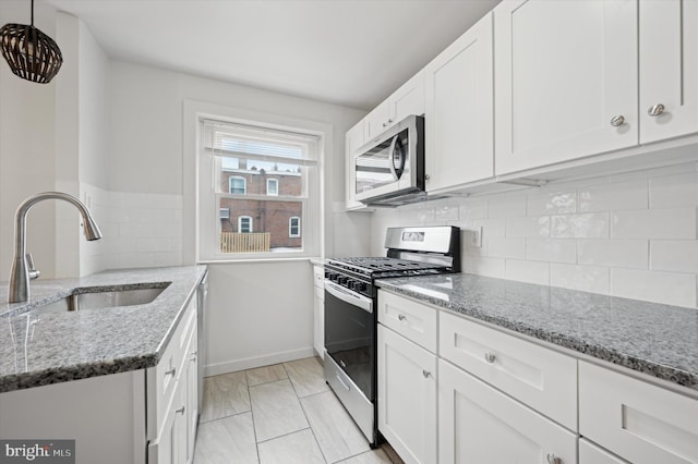 kitchen with white cabinetry, stainless steel appliances, sink, and light stone counters